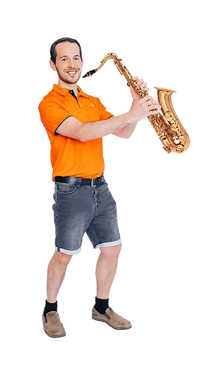 Andreas Kritsch, MSc steht mit einem Saxophon in den Händen und lächelt in die K