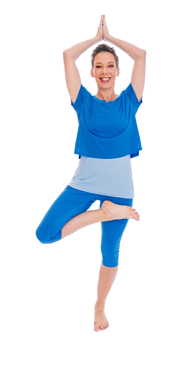 Mag. Dagmar Jiresch steht barfuß in der Baumposition und trägt ein blaues Yoga-O