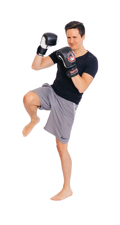 Daniel Mader, MSc (WU) steht in Kampfhaltung mit Boxhandschuhen und hebt das Kni