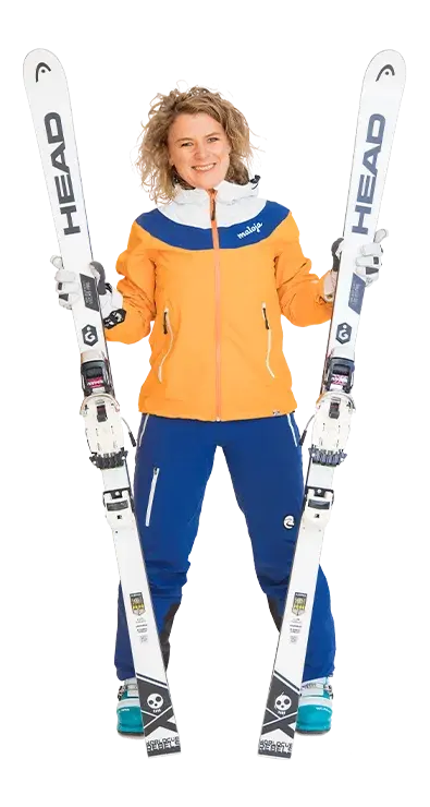 Mag. Heidi Thyri steht in kompletter Skimontur mit orange-blauer Jacke und hält 