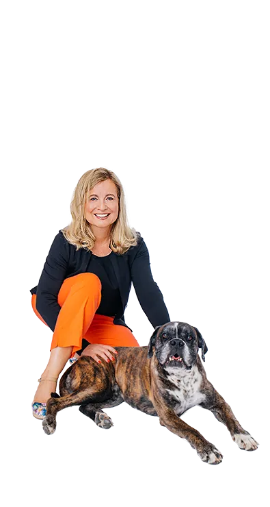 Dipl.-Kff. Dr. Verena Priemer kniet lächelnd neben einem braunen Hund, legt ihm 